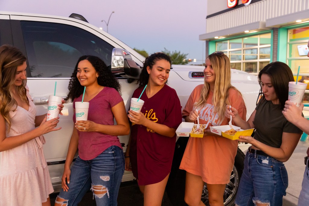 young adults hanging out in front of gilbert az eegee's. tailgating.